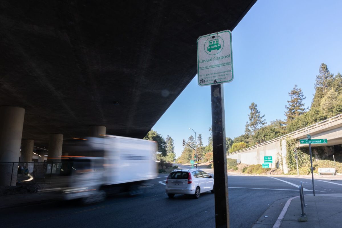 A car and truck pass by a sign for the casual carpool pickup point under Highway 24 in Oakland's Rockridge neighborhood.