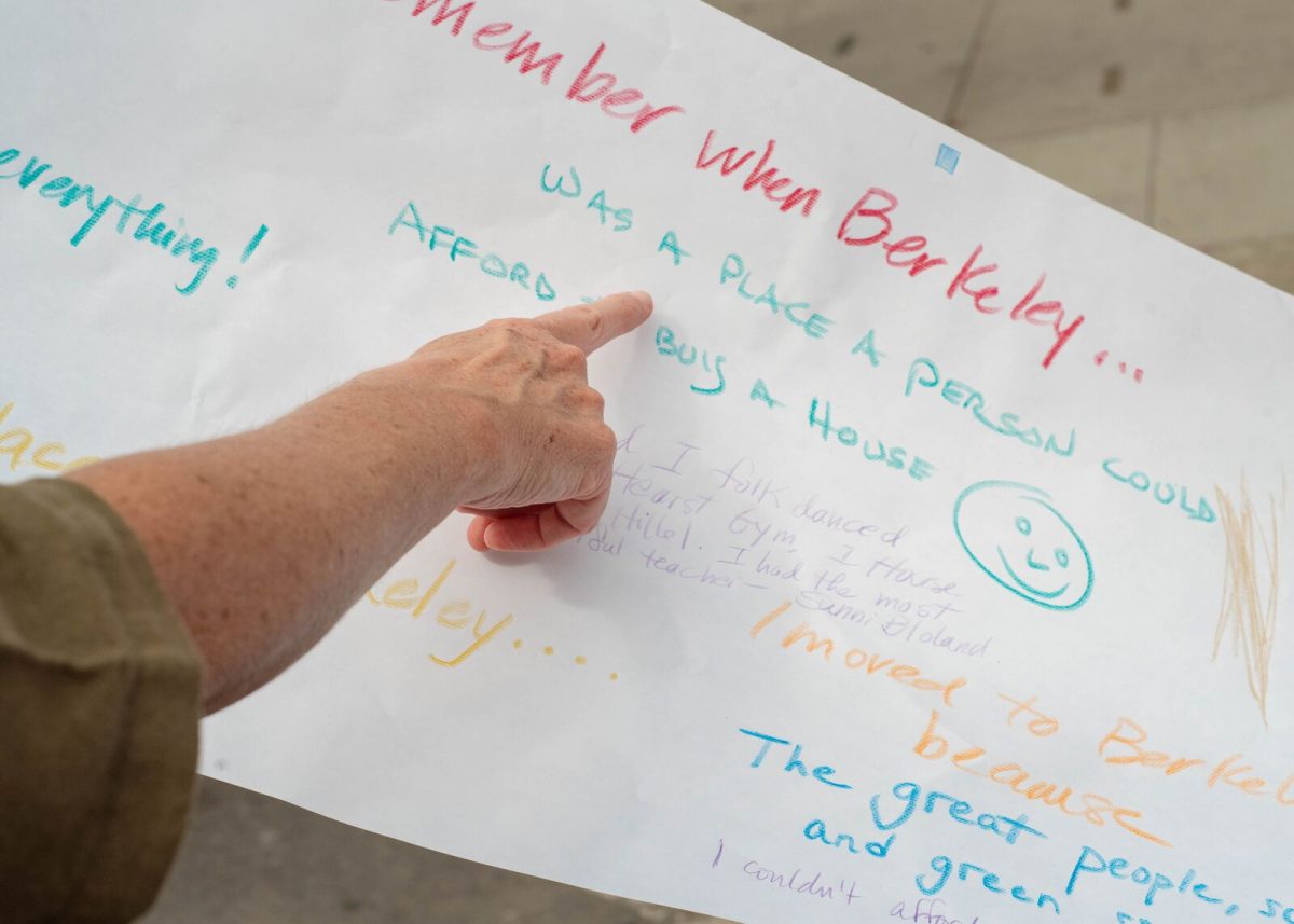 A person points to a piece of paper where someone has written "I remember when Berkeley was a place a person could afford to buy a house."