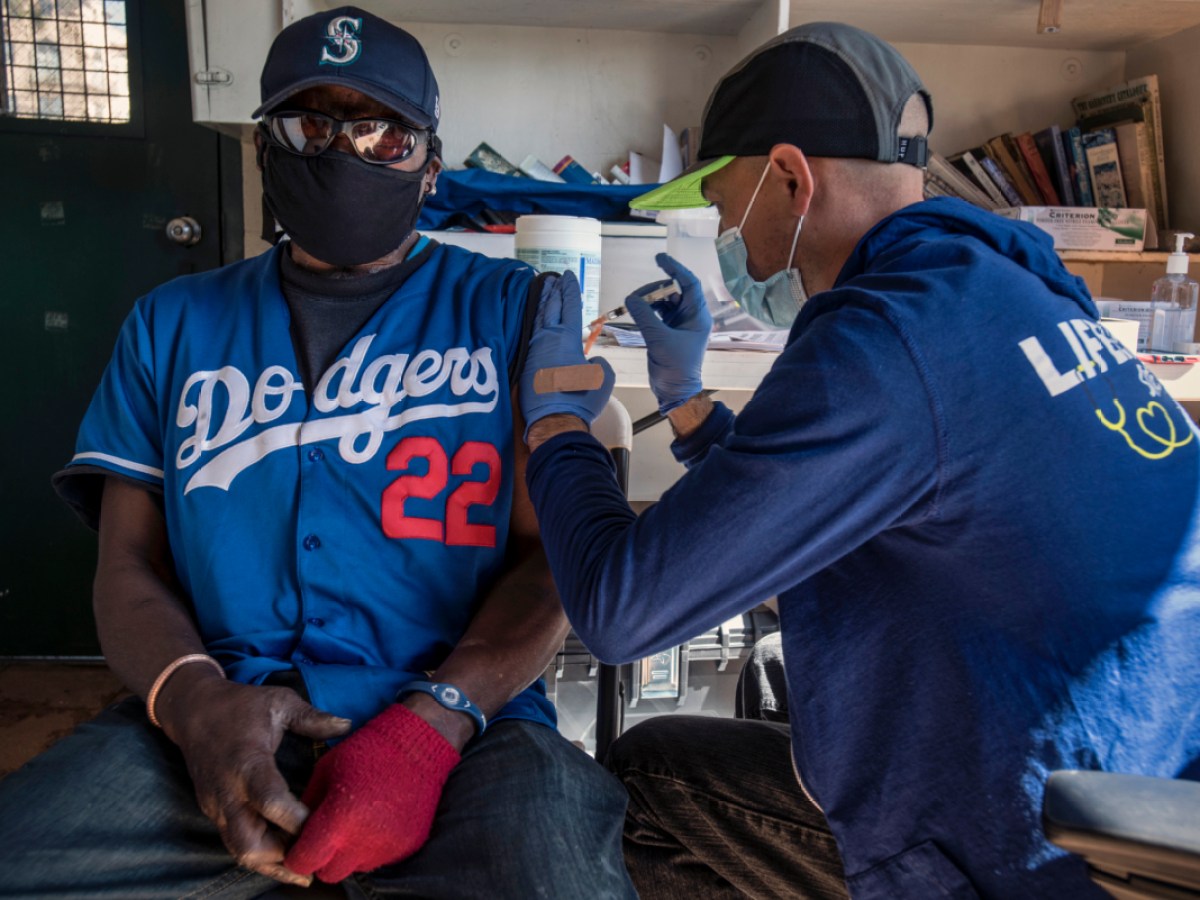 Man in Dodgers shirt getting a vaccination.