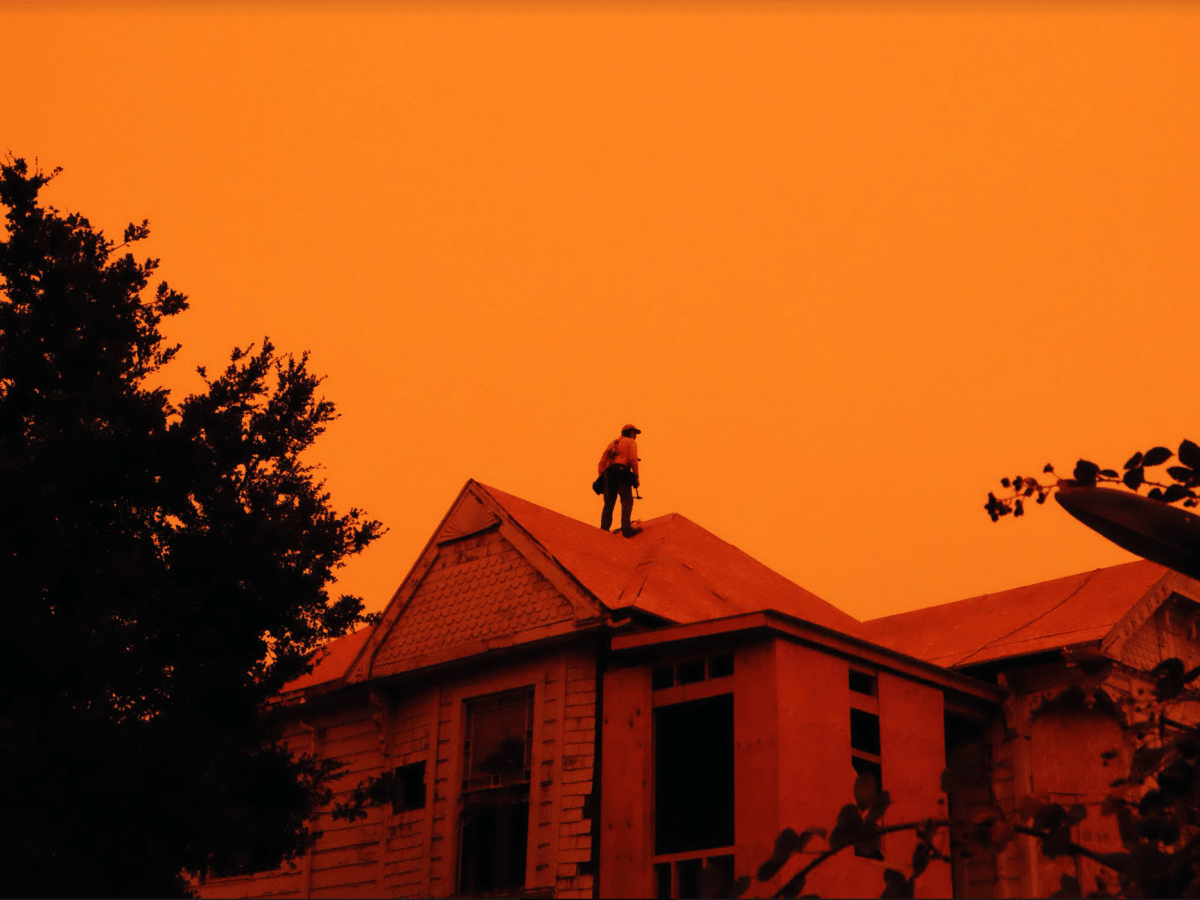 a man standing on the roof of a house in orange light